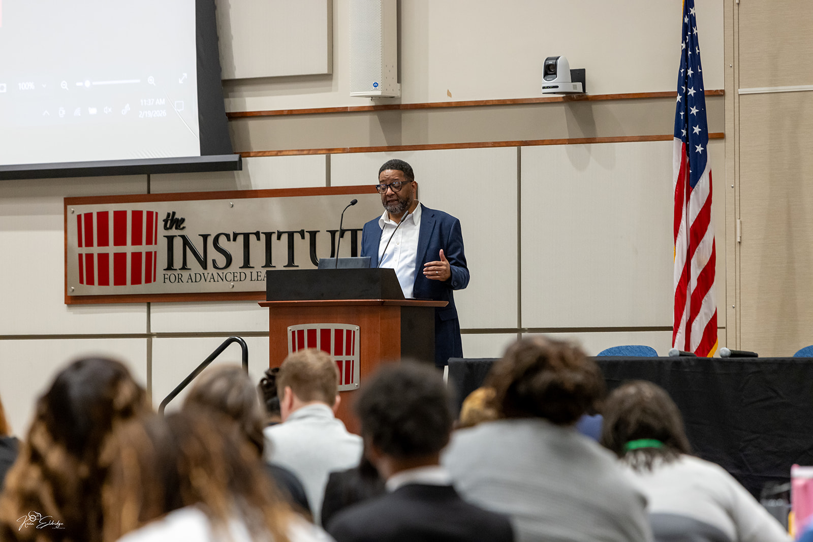 Jonathan McMillan speaking at a podium before a conference audience